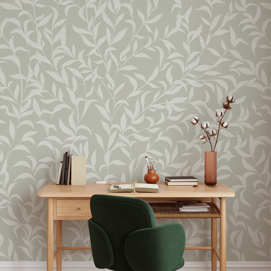 Home office with wooden desk, green chair, and decorative items against a leaf-patterned wall.