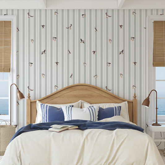 Bedroom with striped wallpaper, wooden headboard, and blue and white bedding.