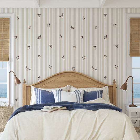 Bedroom with wooden headboard, striped wallpaper, and blue and white bedding.