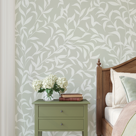 Bedroom with green nightstand, white flowers, and wooden bed against leaf-patterned wall.