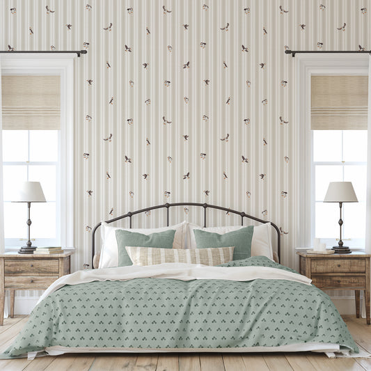 Bedroom with green patterned bedding and striped wallpaper.
