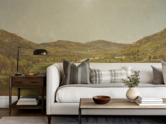 Living room with a white sofa, side table, and coffee table against a scenic wall mural.