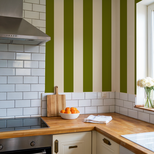 Kitchen with green and white striped wall, wooden countertops, and white cabinets.