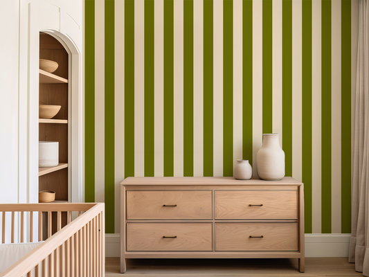 Nursery room with wooden crib, dresser, and shelves against a green and white striped wall.
