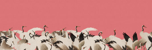 A decorative illustration of a large flock of white cranes with black wingtips and pink beaks, set against a solid dusty pink background with open space at the top.