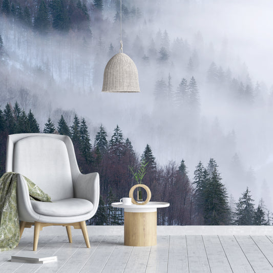 Enchanted Alpine Forest wallpaper in living room with large grey chair and green blanket over chair as well as low hanging wooden lampshade