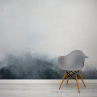 Gray chair with wooden legs against a wall with a gradient design