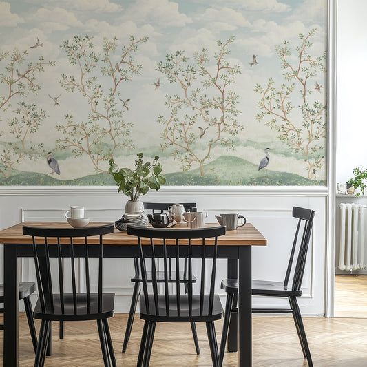 Dining room with a large wall mural of trees and birds, wooden table, and black chairs.