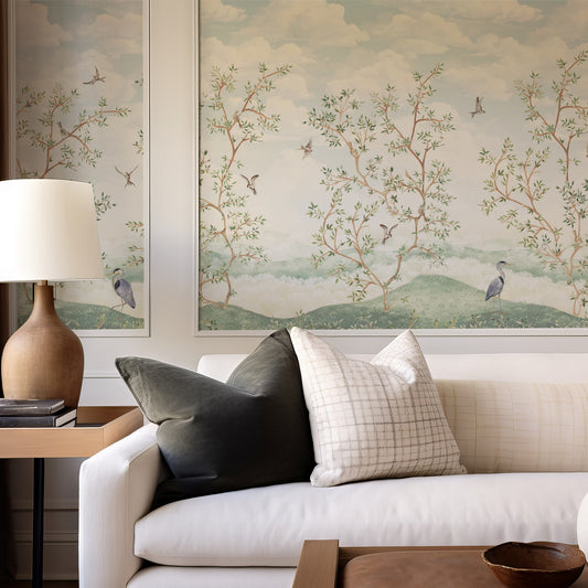 Living room with a white sofa, decorative pillows, and wall art featuring trees and birds.