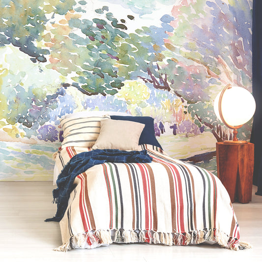 Henri Edmond Cross landscape wallpaper in bedroom with white single bed with red and white stripy bedding with blue and beige cushions and light up globe next to bed on side table