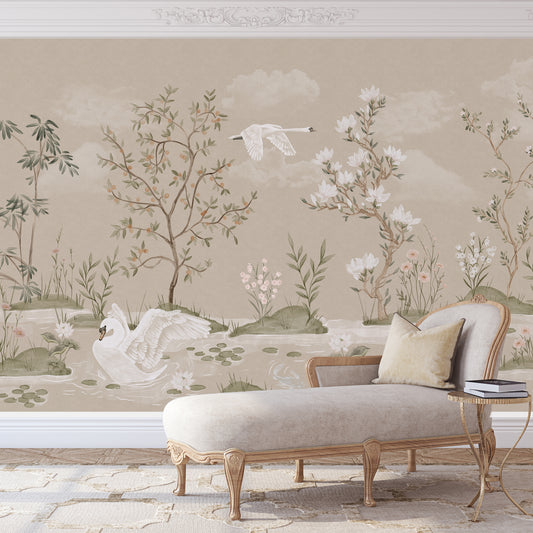 A styled interior scene showing a beige chaise lounge with cream pillows in front of a large wall mural. The mural features a soft botanical landscape with white swans, trees, flowers, and clouds in muted beige, green, and white tones.