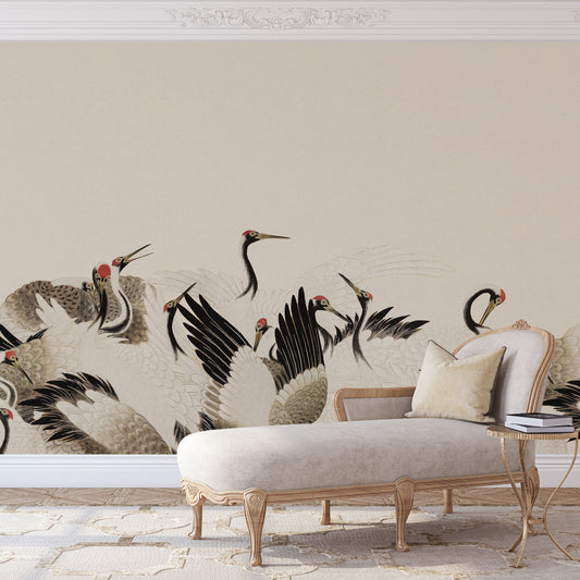 A large wall mural featuring elegant cranes in black, gray, and beige tones, displayed on a beige wall above a cream-colored chaise lounge and a small side table.