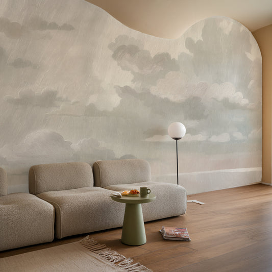Modern living room with a large cloud mural on the wall, featuring a beige sofa and a small round table.