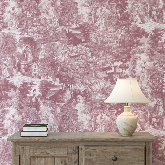 Table with lamp and books against a pink and white toile wallpaper