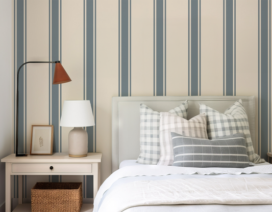 Bedroom with striped wallpaper, bed with plaid pillows, and nightstand with lamp.