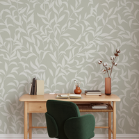 Home office with wooden desk, green chair, and decorative items against a leaf-patterned wall.