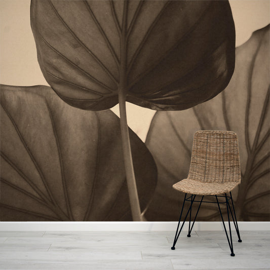 Wicker chair in front of a wall with large brown leaf mural
