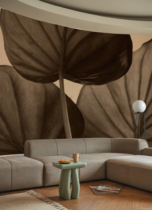 Modern living room with a sectional sofa, decorative table, and large leaf mural.